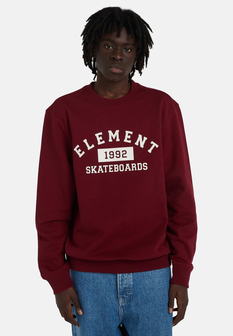 Sweat-shirt bordeaux avec impression blanche "ELEMENT 1992 SKATEBOARDS". Poignets et ourlet côtelés. Tissu doux avec une coupe décontractée, associé à un jean bleu clair.