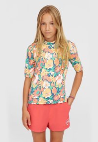 Färgglad blommig rash guard med korta ärmar, har en blandning av rosa, gula och gröna blommor på en mörk bakgrund; matchas med korallfärgade shorts.