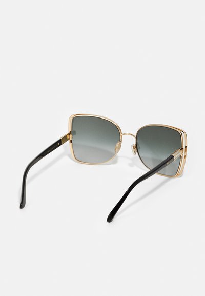 Sluneční brýle se čtvercovým designem, šedými čočkami, zlatým kovovým rámem a černými plastovými spánky. Disponují nosními podložkami a značkováním na spáncích.