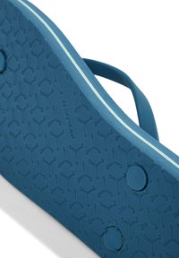 Blå flip-flop sål med en struktureret gummioverflade, der har et honningkombmønster, og en kontrasterende lyseblå stribe langs kanten.