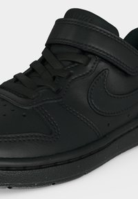 Mustast nahast Nike toss paeltega ja takjakinnitus, näidates külje ja esiosa detaile lähedalt.