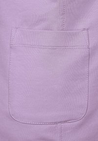 Lilac fabric featuring a patch pocket with rounded edges, smooth texture, and visible stitching outlining the pocket and garment seam.
