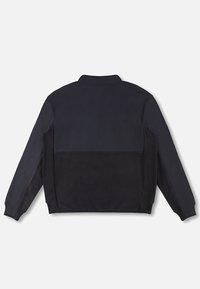 Veste polaire noire à manches longues, poignets côtelés et col montant, vue de dos sur un fond clair.