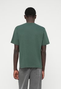 T-shirt z krótkim rękawem, zielony, z okrągłym dekoltem, wykonany z bawełny, o luźnym kroju ze prostym obszyciem i minimalną ilością szwów.
