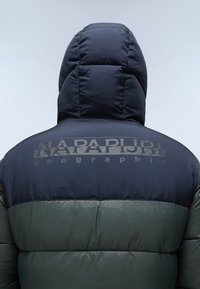 Padded hooded jacket with a navy upper section and green lower section. Features a logo print on the back in a contrasting color.