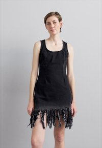 Musta farkkutunika, jossa on istuva yläosa ja fringed helma. Sisältää pyöreän kaula-aukon, hihattoman muotoilun ja raidan reunan yksityiskohtia alaosassa.