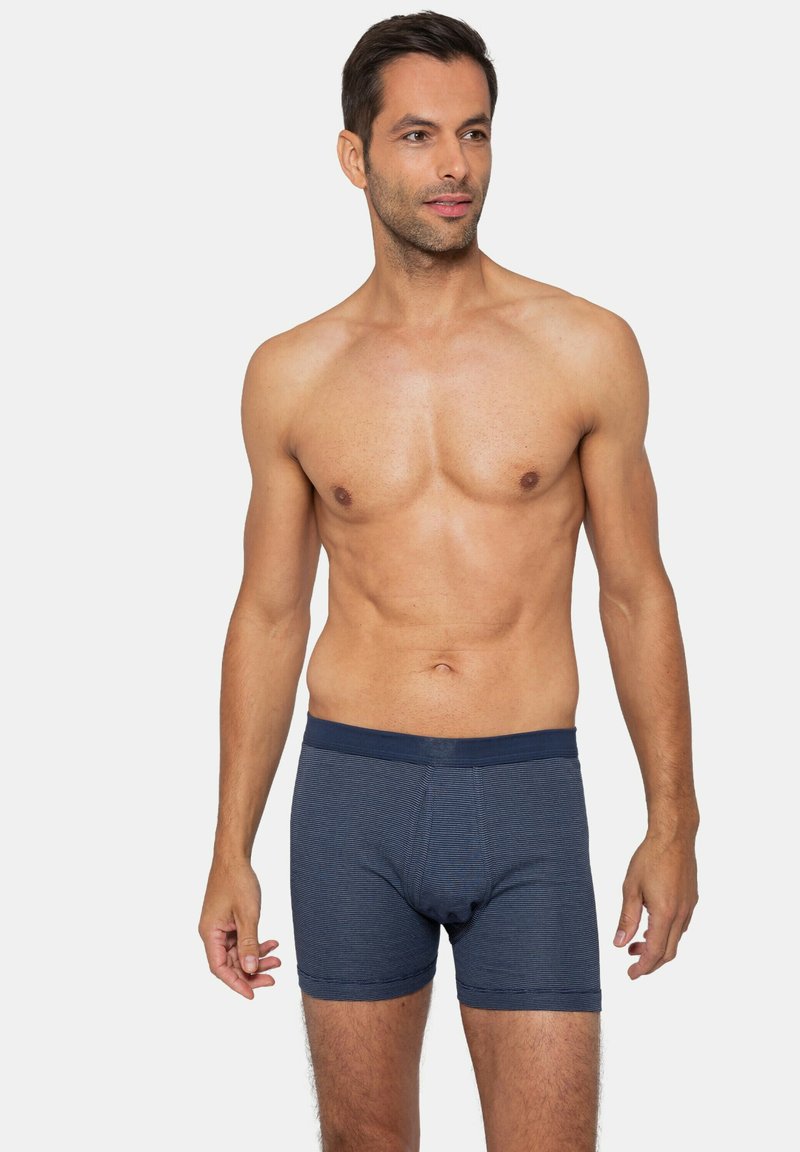 Marinblå boxerkalsonger med ett texturerat, randigt mönster och elastiskt midjeband. De sitter tight mot kroppen och tyget verkar mjukt och elastiskt.