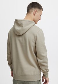 Beige hoodie met een relaxed fit, uitgerust met een kangoeroezak en ribgebreide manchetten en onderrand, gemaakt van een zachte katoenen mix stof.