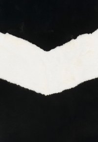 Zwart-wit tapijt met een chevronpatroon. Zacht, donzig wit wol in het midden contrasteert met gladde zwarte randen.