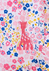 Il tessuto bianco presenta un motivo floreale in rosa, blu e giallo. Una giraffa ricamata in rosa è in evidenza. Si possono notare dettagli con bordo arricciato.