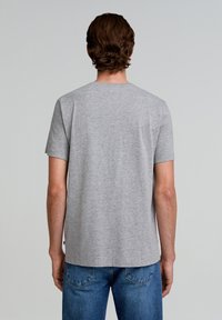 Grijze t-shirt met korte mouwen en een ronde halslijn. Gemaakt van zachte, gestructureerde stof. Gecombineerd met blauwe spijkerbroek. Eenvoudig ontwerp, geen patronen.