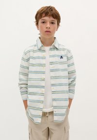 Camicia a maniche lunghe con bottoni di colore bianco, con strisce orizzontali blu e verdi, caratterizzata da un piccolo logo a forma di teschio blu sul petto.