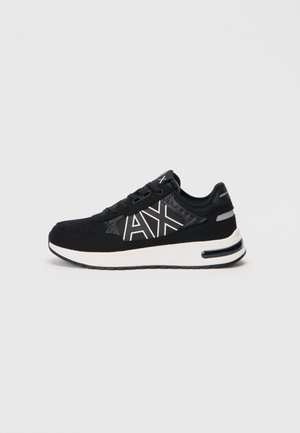 Zapatilla deportiva negra con parte superior de malla texturizada, detalle del logo en blanco y suela acolchada. Presenta un diseño elegante y acentos en contraste.