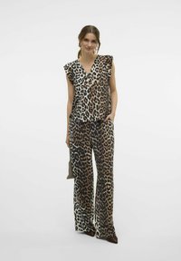 Ensemble à motif léopard avec un haut à col en V et des manches volantées, associé à un pantalon large assorti dans des teintes de marron, crème et noir.