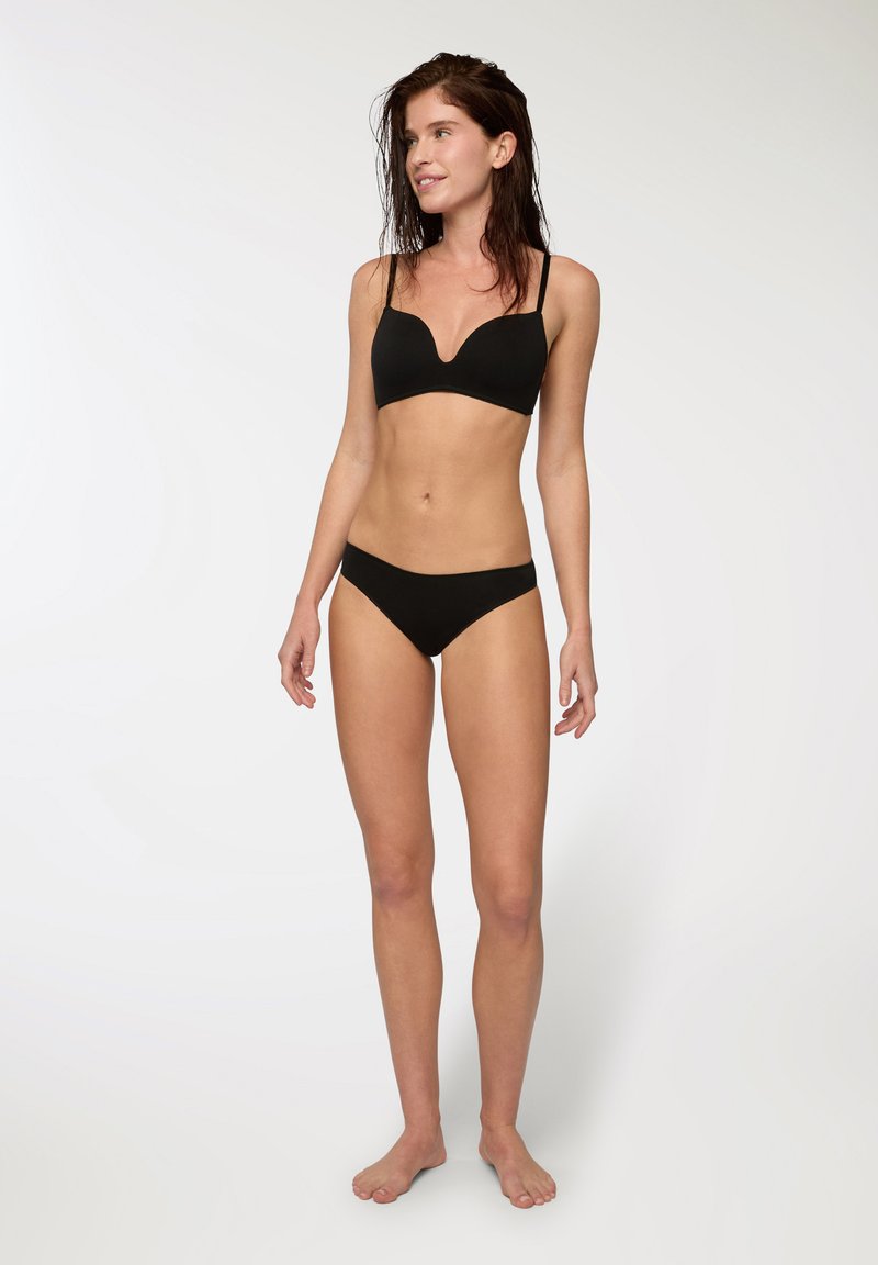 Completo bikini nero con reggiseno a bralette a V profonda e spalline sottili, abbinato a slip a vita bassa, realizzato in materiale liscio e elasticizzato.