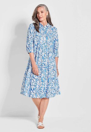 Kleid mit blauem Blumenmuster, Knopfleiste, Dreiviertelärmeln und schwingendem Rock. Hergestellt aus leichtem Stoff. Akzentuiert mit hellblauen Knöpfen.