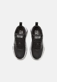 Zapatillas de cuero negro con acentos blancos, puntera redondeada, collar acolchado y marca en la lengüeta. Suela de goma con textura en la banda de rodadura.