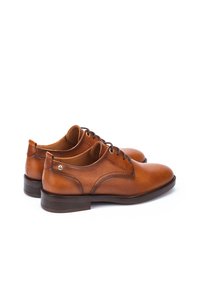Chaussures habillées en cuir marron avec un bout arrondi, un design à lacets et de subtils détails de couture. Elles présentent une finition lisse et une semelle discrète.