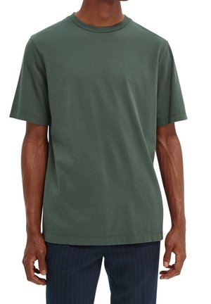 Krótki rękaw, t-shirt z okrągłym dekoltem wykonany z ciemnozielonej bawełny. Gładka faktura, luźny krój oraz przeszywane krawędzie. W połączeniu z ubraniem w paski.