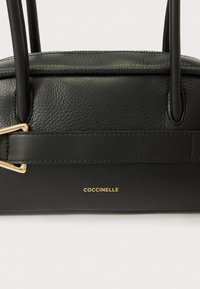 Bolso de cuero negro con acabado texturizado, detalles en hardware dorado y logo de la marca visible; cuenta con dos asas resistentes.