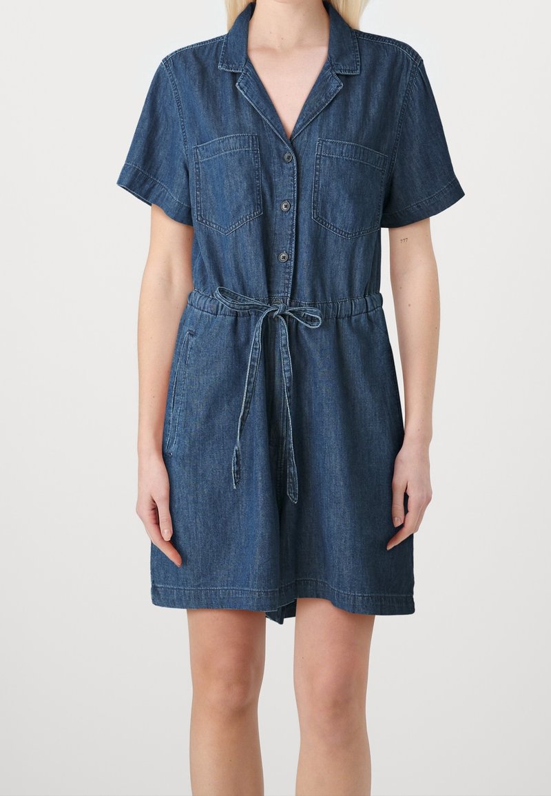 Robe-chemise en denim bleu foncé, avec manches courtes, deux poches poitrine, fermeture par boutons et ceinture à nouer pour un ajustement personnalisé.