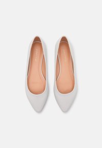 Flats blanches à bout pointu en matériau lisse, dotées d'une semelle intérieure beige douce avec "ANNA FIELD" embossé. Design minimaliste sans éléments métalliques.