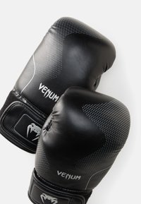Luvas de boxe pretas com couro texturizado, apresentando um padrão cinza pontilhado e o logótipo "Venum" em branco. Fecho de velcro duplo para um ajuste seguro.