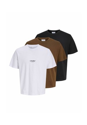 Un giovane uomo indossa una t-shirt bianca JJ Studios, pantaloni beige e sneakers marroni davanti a uno sfondo chiaro e uniforme.