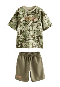 Kurzer Camouflage-Print T-Shirt in Grüntönen mit kontrastierendem orangefarbenem Text, kombiniert mit olivgrünen Shorts mit elastischem Bund.