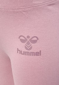 Hellrosa Sportleggings mit einem matten Logo-Design in einem dunkleren Farbton, das eine glatte Textur und eine enganliegende Form betont.
