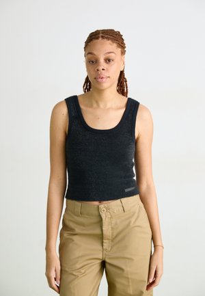 Un top de tip tank, negru, ajustat, cu decolteu rotund și margini ribbate, realizat dintr-un material moale și texturat, purtat cu pantaloni kaki.
