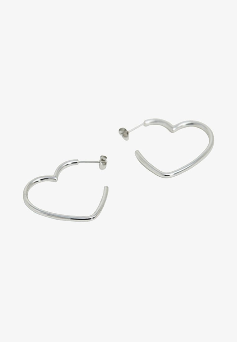 Boucles d'oreilles créoles en forme de cœur en métal argenté avec fermoirs à tige, sur fond blanc.