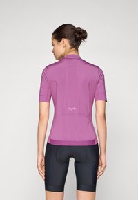 Maillot de cyclisme à manches courtes en tissu violet vibrant, avec un design ajusté, des détails de couture subtils, et un logo dans le bas du dos.