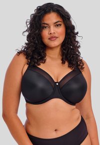 Soutien-gorge noir avec des bonnets lisses et rembourrés, orné de détails en maille transparente et d'un embellissement central. Comprend des bretelles larges et des bords sans couture.