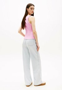 Roze geribde tanktop en lichtblauwe wijde jeans met hoge taille, twee achterzakken en beige plateau sneakers.