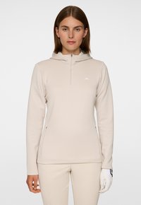 Felpa cappuccio zip beige chiaro con una texture morbida, dotata di zip frontale, cappuccio e logo discreto sul petto. Design slim fit.
