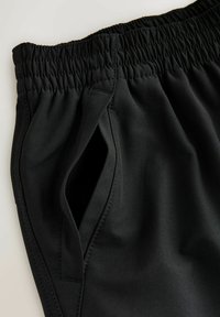 Black athletic shorts with a stretchy waistband, featuring a side pocket and smooth, lightweight fabric texture. Seam detailing visible.