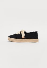 Espadrillas in tela nera con bordi sfilacciati, lacci in nastro beige e una suola intermedia in iuta intrecciata. Presenta un piccolo etichetta color nocciola sul lato.
