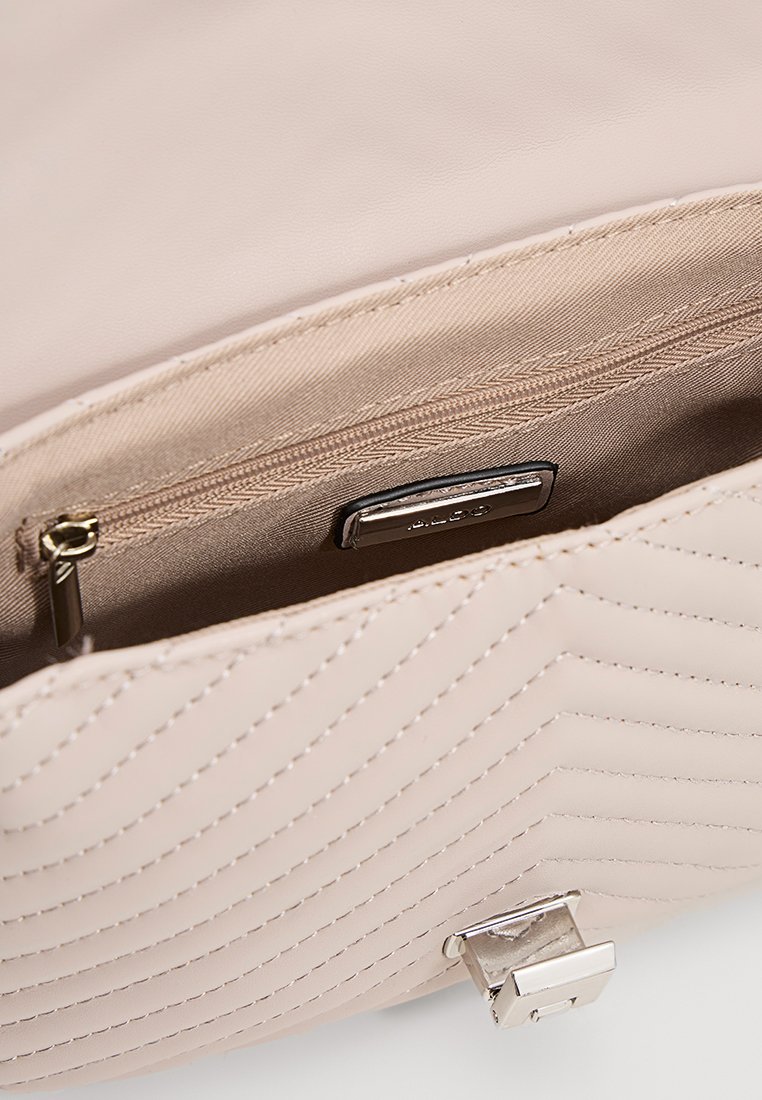 Quilted beigem Handtasche mit glatter Oberfläche, ausgestattet mit einem silbernen Metallverschluss, einer Innen-Reißverschlusstasche und einem weichen Stofffutter.