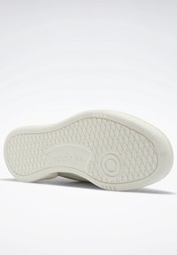 Vit Reebok-sneakersula med diamantmönstrad grepp, cirkulärt detaljer nära ballen och Reebok-logotyp präglad i mitten.