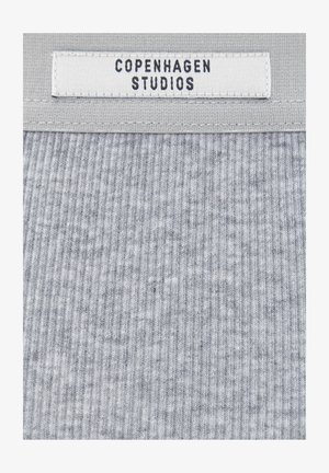 Grauer, gerippter Stoff mit einem weißen eingenähten Etikett, auf dem "COPENHAGEN STUDIOS" in schwarzen Großbuchstaben steht.
