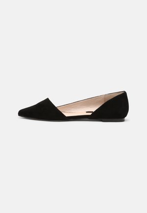 Chaussure plate noire en daim à bout pointu avec un design ouvert sur les côtés et doublure intérieure beige sur un fond clair.
