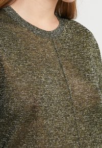 Pull olive vert scintillant avec un col rond, des fils métalliques fins et une texture de tricot légèrement lâche, offrant un éclat subtil.