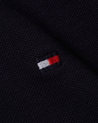 Morska tkanina s teksturiranim tkanjem koja sadržava mali izvezeni logotip u crvenoj, bijeloj i plavoj boji smješten na rubu.
