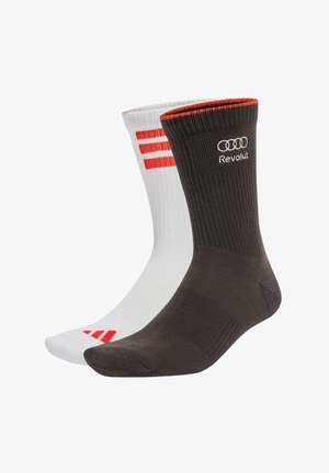 Para skarpetek sięgających do połowy łydki, jedna czarna z czerwonym wykończeniem i białym logo "Revolut", druga biała z czerwonymi paskami i trójkątnym wzorem.