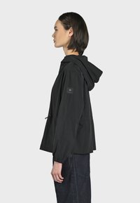 Giacca nera con cappuccio, dotata di cordino, maniche lunghe e polsini elasticizzati. Presenta un tessuto strutturato e una toppa logo laterale.