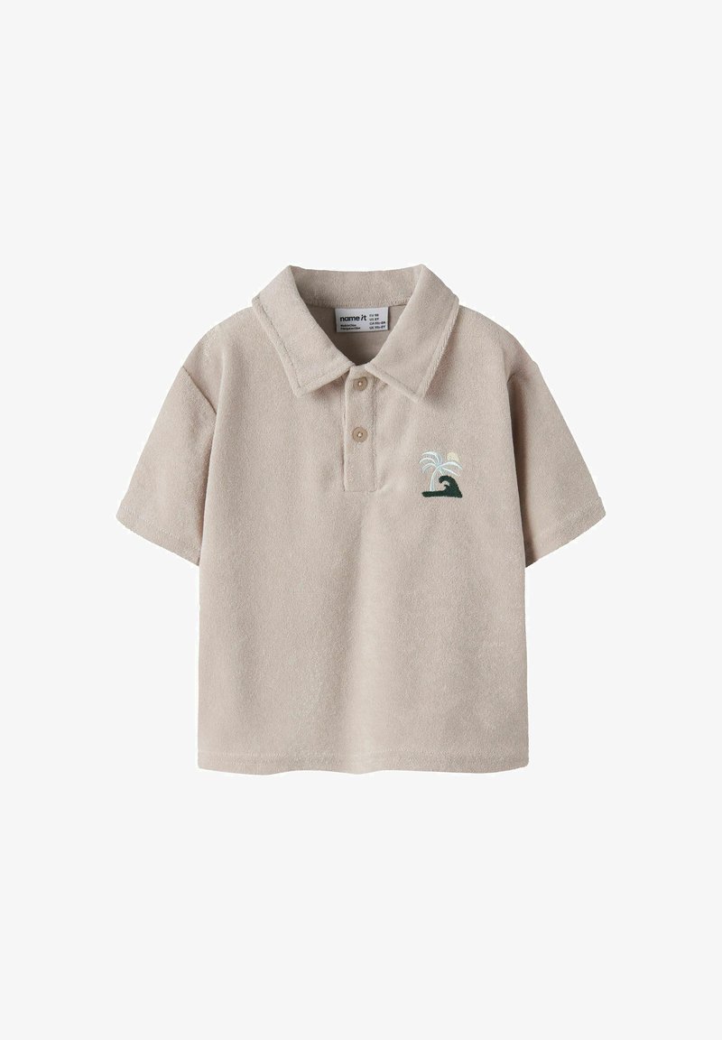 Polo beige à manches courtes avec col, deux boutons, et une petite vague verte brodée avec un palmier blanc sur la poitrine.