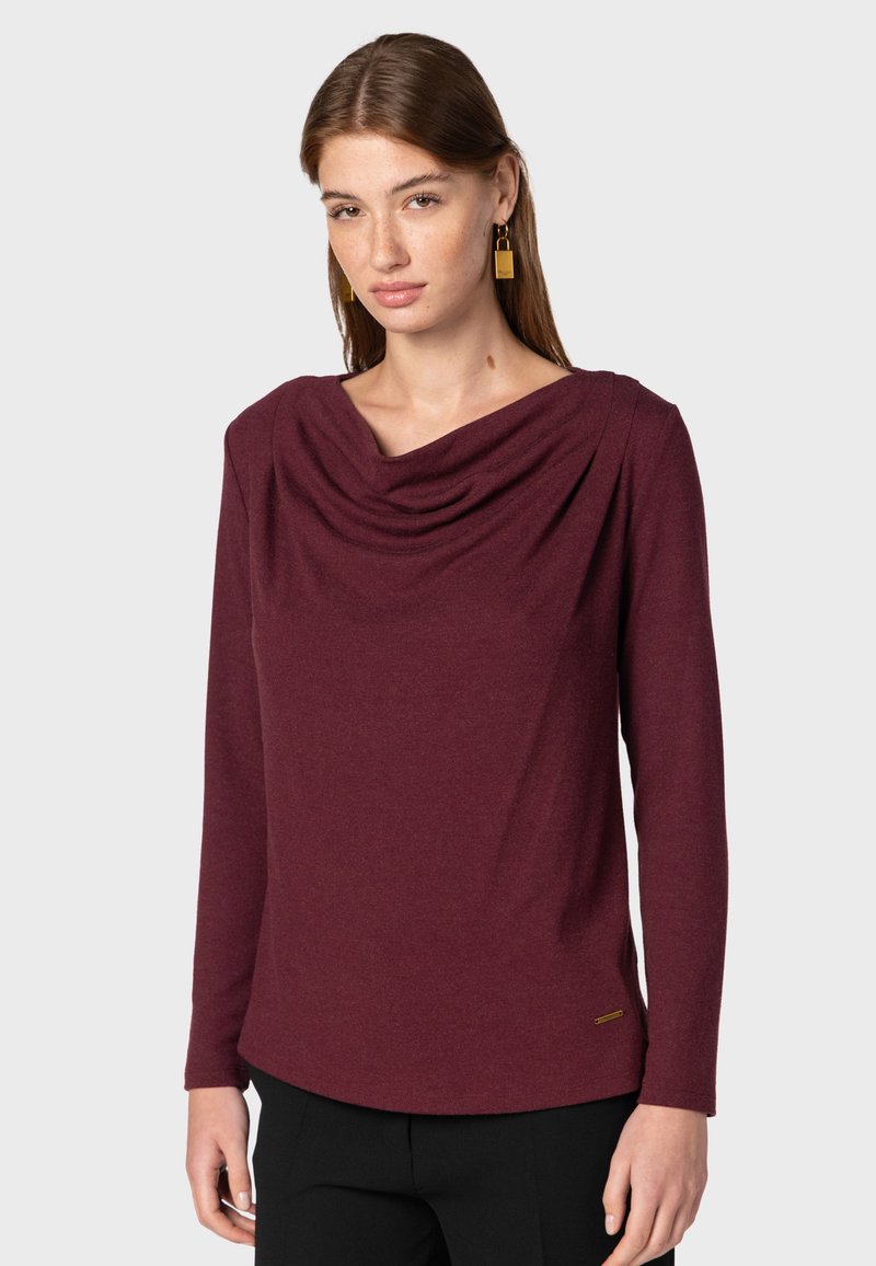 Długi rękaw bluzka w głębokim burgundowym kolorze z luźnym dekoltem typu cowl i zaokrąglonym dołem. Wykonana z miękkiego materiału z minimalnymi detalami przeszycia.