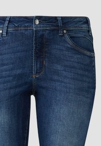 Donkerblauwe denim jeans met een getailleerd ontwerp, voorzien van een ritssluiting, vijf zakken en contrasterende stiksels langs de naden.