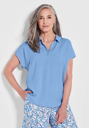 Blouse bleu clair à manches courtes avec un col en V et une coupe décontractée ; texture lisse, assortie à un pantalon bleu clair à motifs au design abstrait.